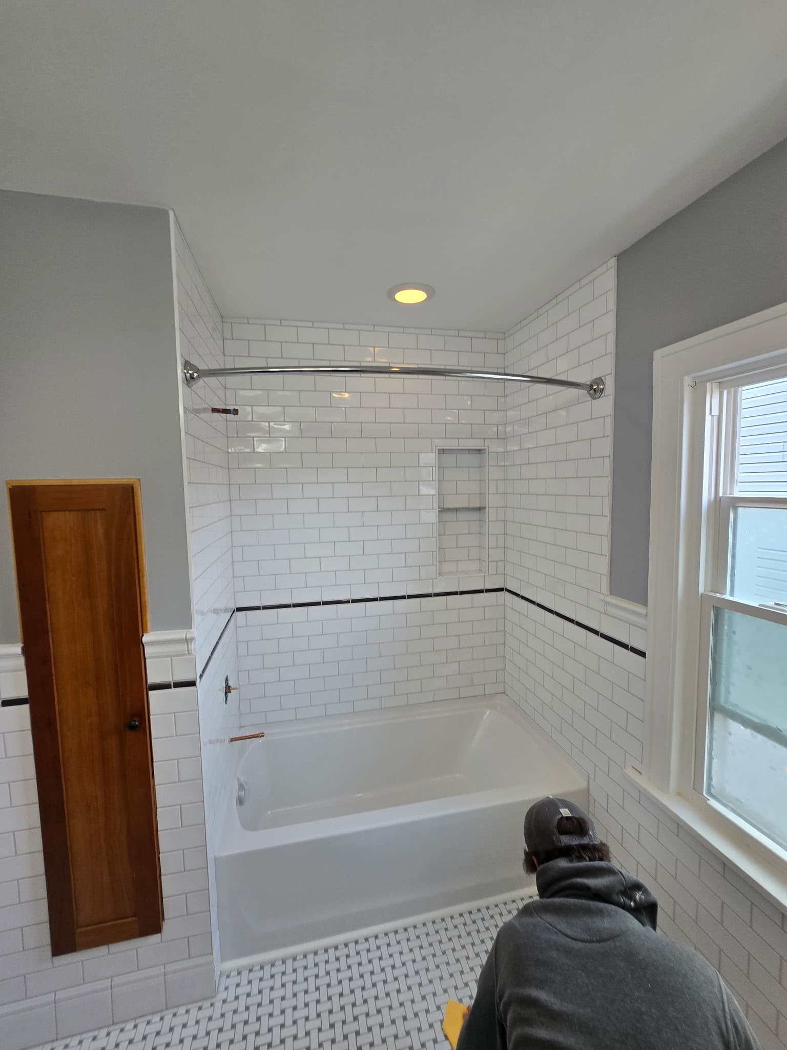 Classic bathroom with subway tile, black accent stripe, basketweave hex tile floor, and tub