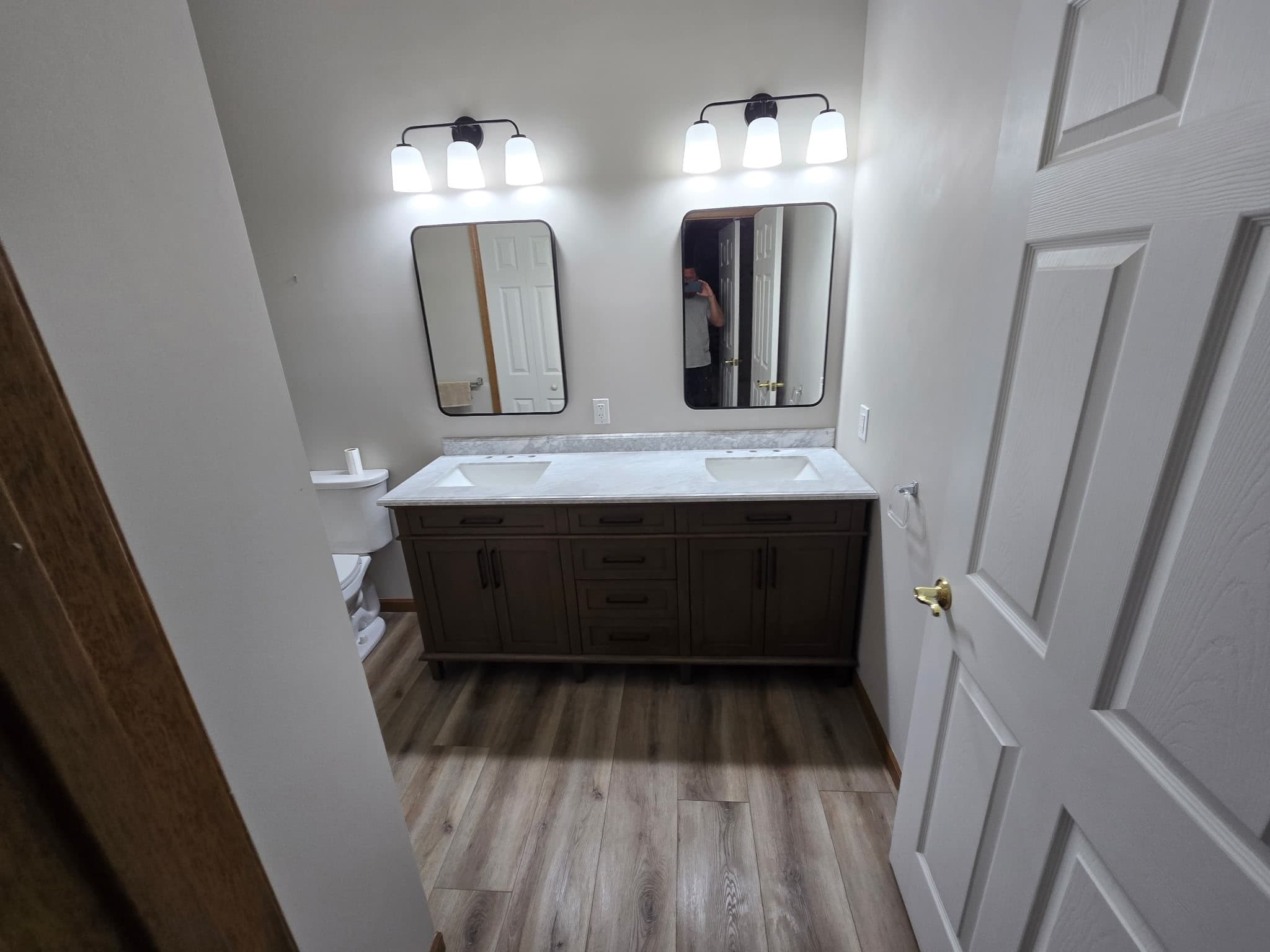 Modern bathroom with dark wood double vanity, marble counter, and twin black mirrors