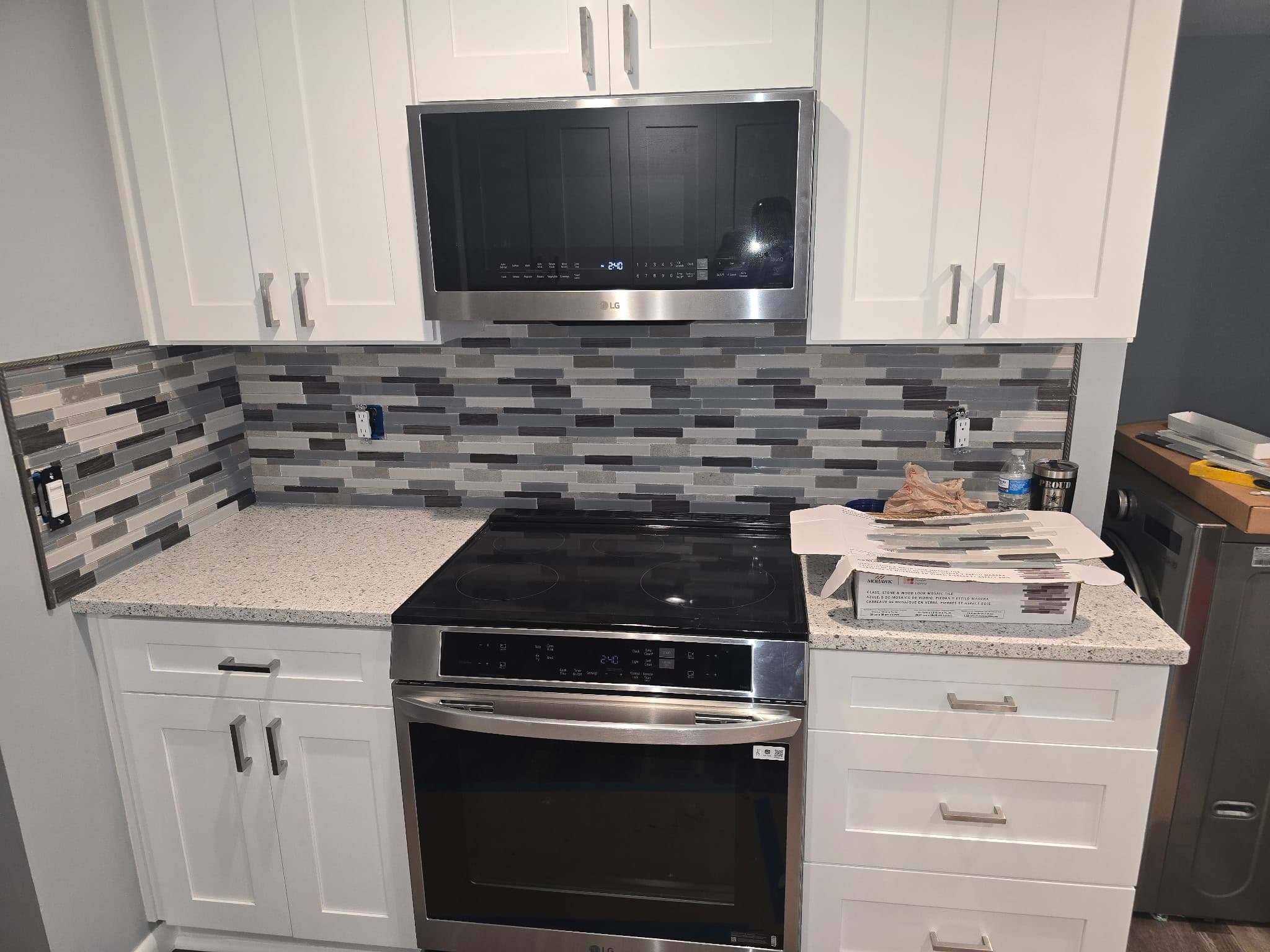 White shaker kitchen with linear glass mosaic backsplash and stainless range