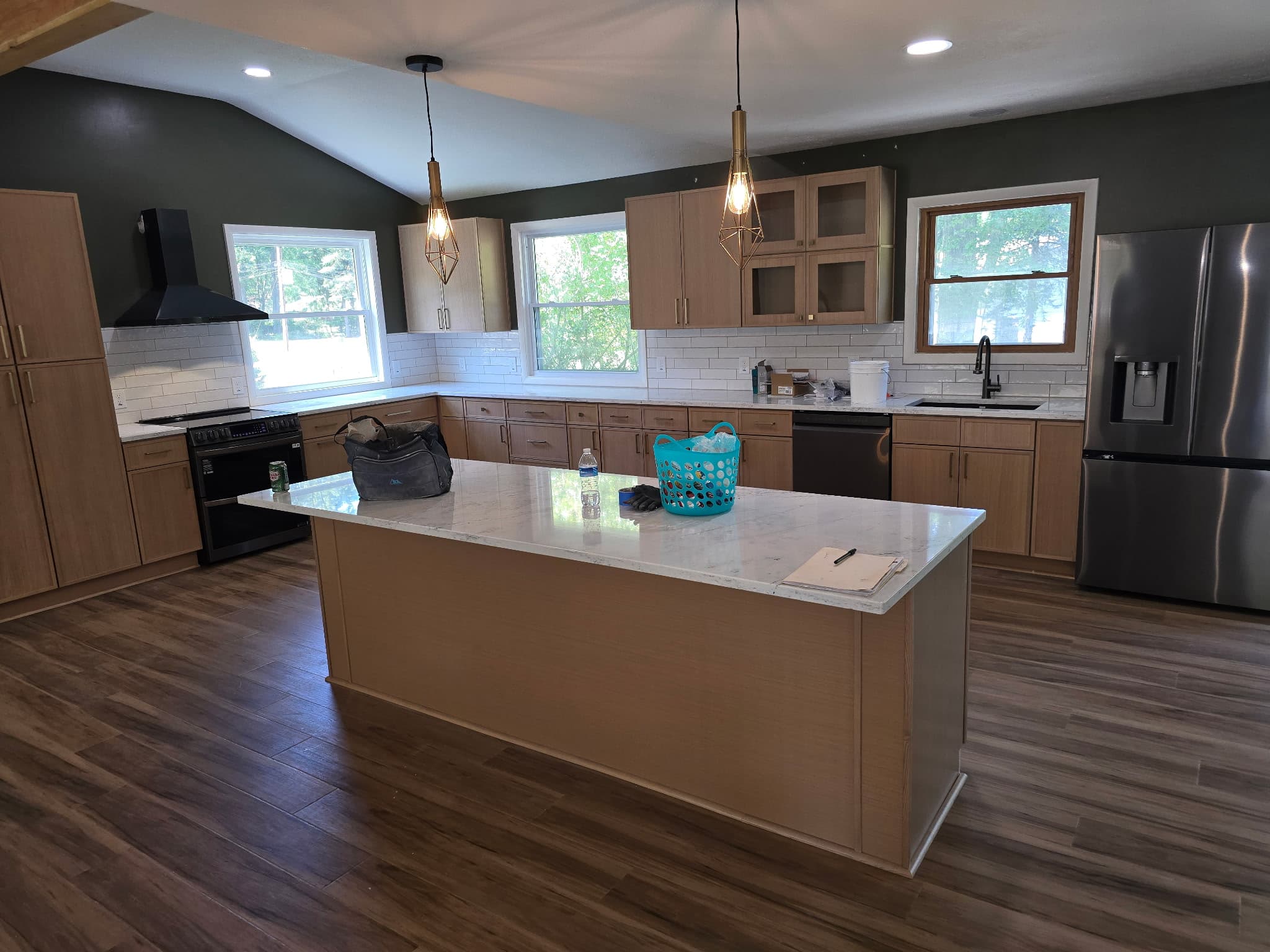 Open-concept room with vaulted ceiling, dark green walls painted clean to the trim