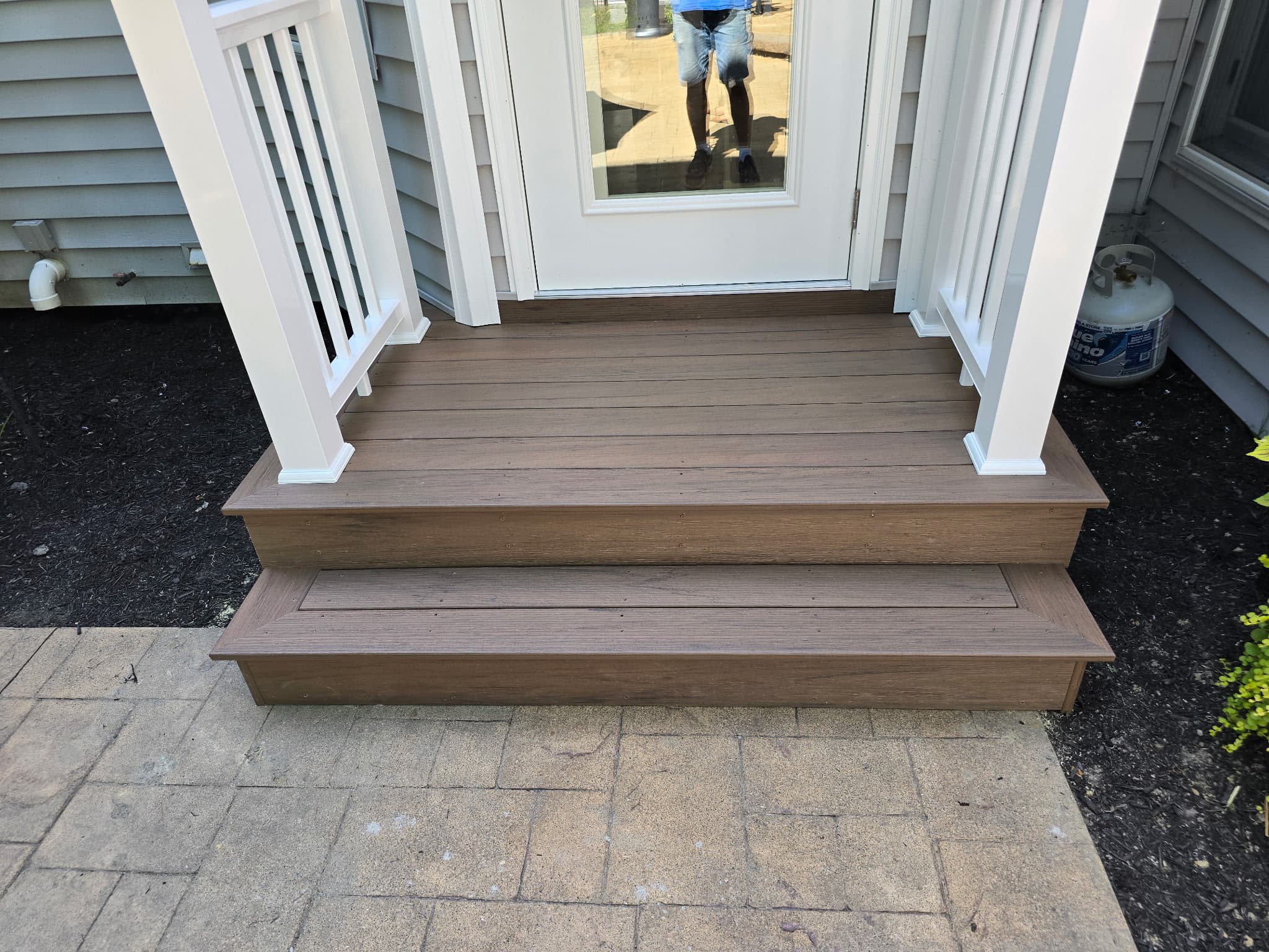 Composite deck and front porch steps with white columns and railing by 8 Is Enough Construction Lorain County OH