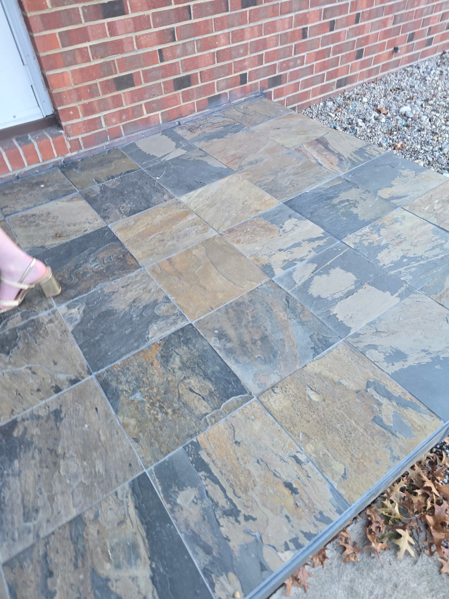 Multi-tone slate stone landing leading off a back deck at a brick home