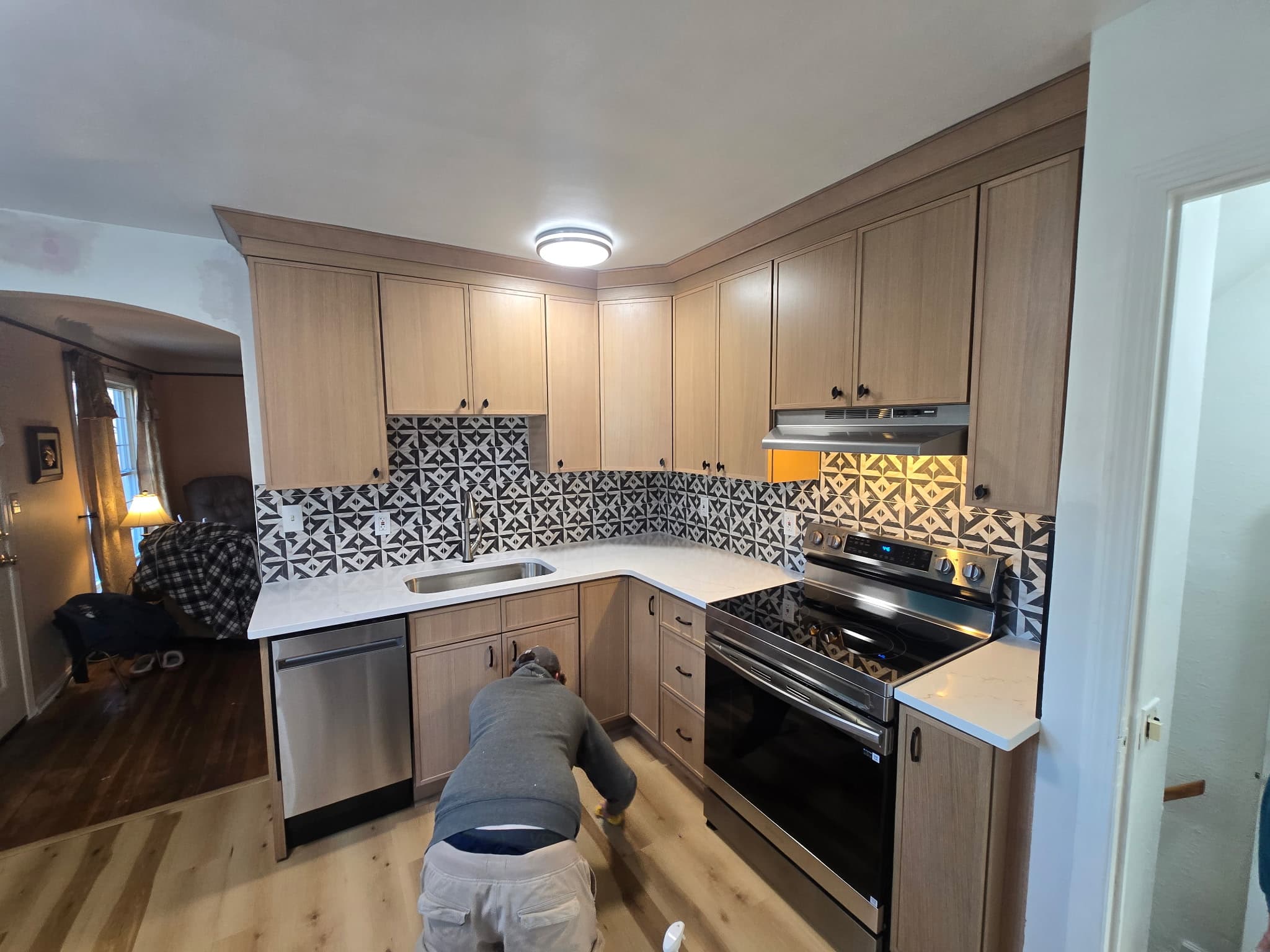 Crew installing flooring in a freshly painted oak shaker kitchen with patterned tile backsplash